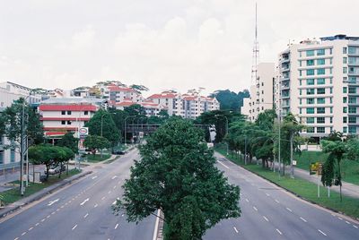 Road amidst trees in city against sky