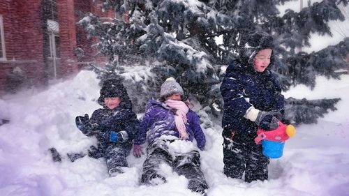 Happy children playing in snow covered yard