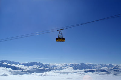 Overhead cable car over snowcapped mountains against sky