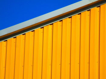 Low angle view of yellow wall against clear blue sky