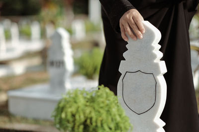 A hand touching the white marble tombstone at a muslim cemetary