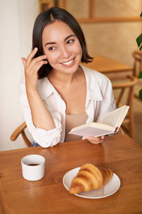 Portrait of young woman sitting on table