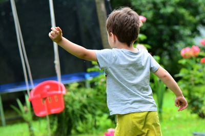 Rear view of boy standing by swing at park