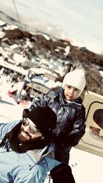 Man with son wearing warm clothing while standing on snow covered land