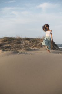 Woman standing on beach against sky