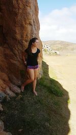 Full length of young woman on rock against sky