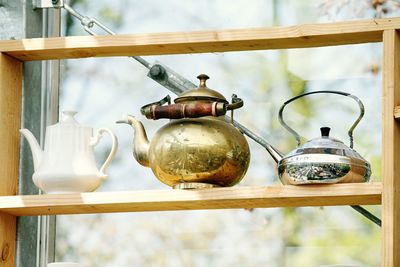 Close-up of kettles on wooden shelf