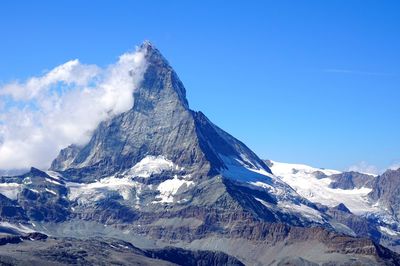 Scenic view of snowcapped mountains against blue sky