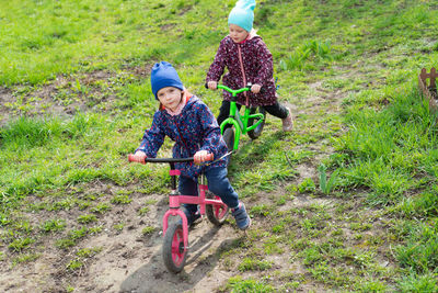 Two children ride balance bikes outdoors. childhood in the countryside or in the backyard.