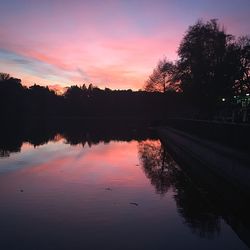 Silhouette trees by lake against sky during sunset