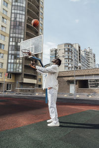 Young man throwing basketball at sports court