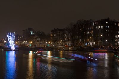 Illuminated bridge over river in city at night