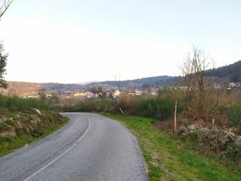 Road amidst trees against clear sky