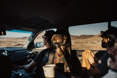 Friends sitting in car against mountain