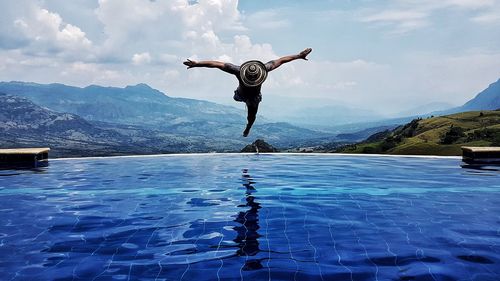 Man jumping in swimming pool against sky