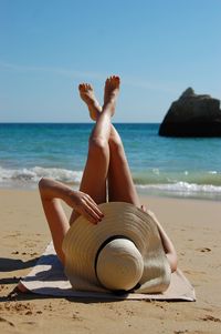 Woman sunbathing at beach against sky