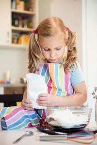 Cute girl preparing food on table at home