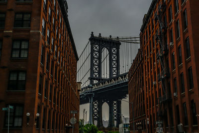 Low angle view of bridge and buildings against sky