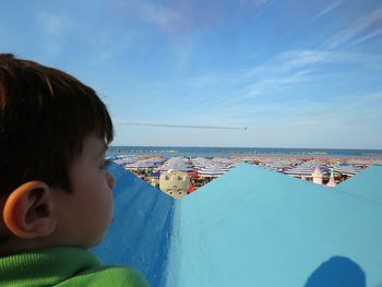 Rear view of boy watching airshow against sky