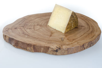 Close-up of bread on tree stump against white background