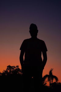 Silhouette man standing against orange sky