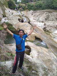 Full length portrait of smiling boy on rock