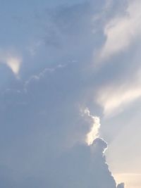 Low angle view of sunlight streaming through clouds