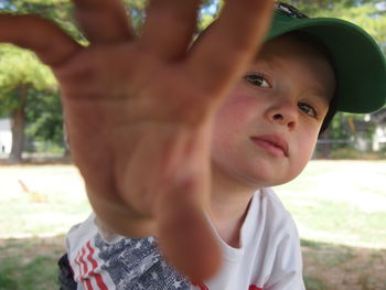 Portrait of boy gesturing stop sign on field