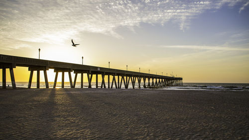 Pier over sea against sky during sunset