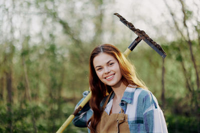 Portrait of young woman standing against trees