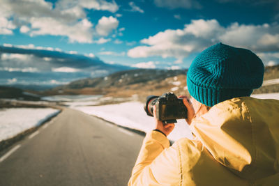 Rear view of man photographing against sky