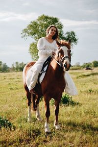 Young woman riding horse on field