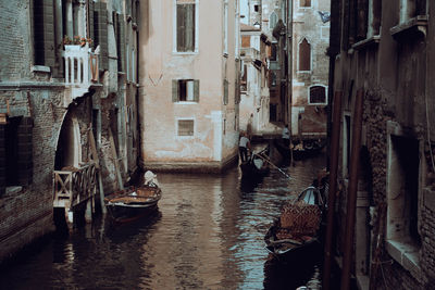 Boats moored in canal amidst buildings in city