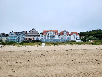 Houses on beach by buildings against sky