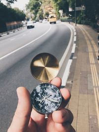 Cropped hand holding navigational compass on road