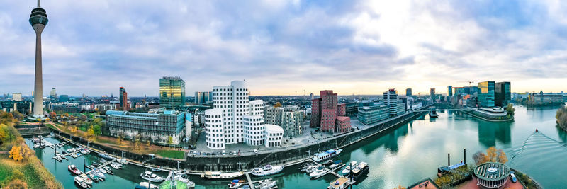 Panoramic view of buildings in city against cloudy sky