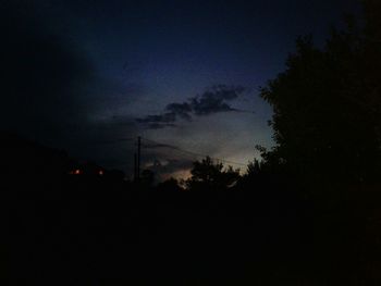 Silhouette of factory against sky at night