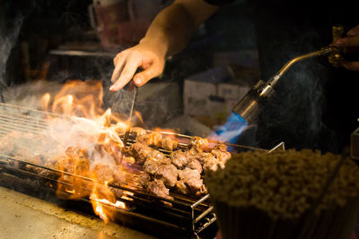 Close-up of man preparing food on barbecue grill