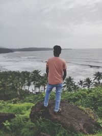 Rear view of man looking at sea against sky