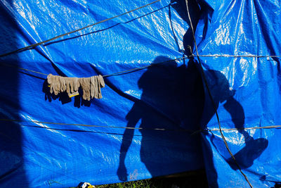 Close-up of man hanging against blue sky