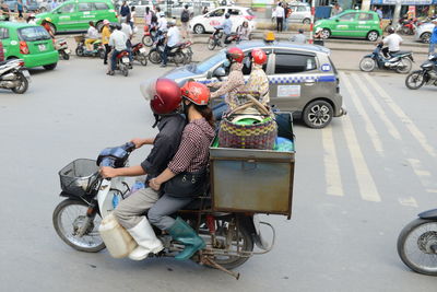 People riding motor scooter on road