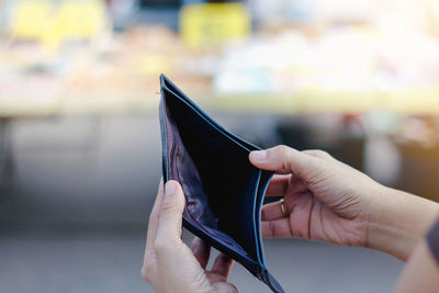 Close-up of woman holding empty wallet outdoors