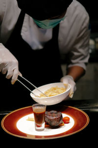 Close-up of chef arranging food in plate at restaurant