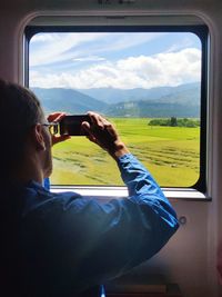 Man photographing while standing by train window