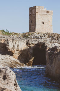 Old building by sea against clear sky