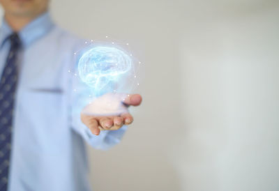 Digital composite image of businessman holding illuminated brain