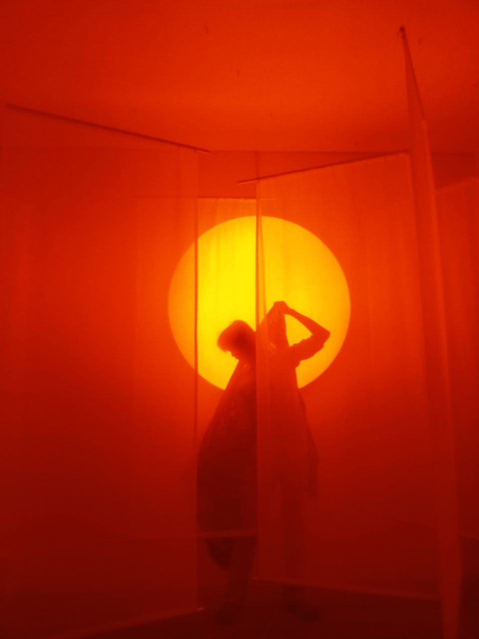 red, yellow, light, lighting, silhouette, orange, indoors, one person, orange color, illuminated, standing, lighting equipment, circle, wall - building feature, adult