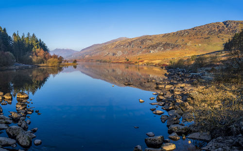 Scenic view of lake and mountains against blue sky