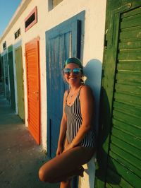 Portrait of woman wearing sunglasses while standing by beach houses