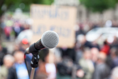 Close-up of microphone against crowd in city
